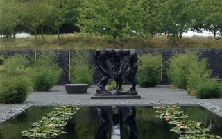 Three statues located near a pond in a garden